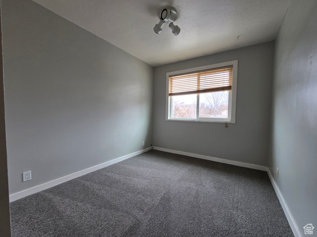 Empty room featuring a textured ceiling, baseboards, and carpet floors