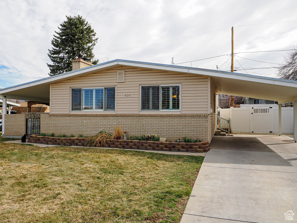 View of front of property featuring a front lawn, driveway, a gate, fence, and a carport