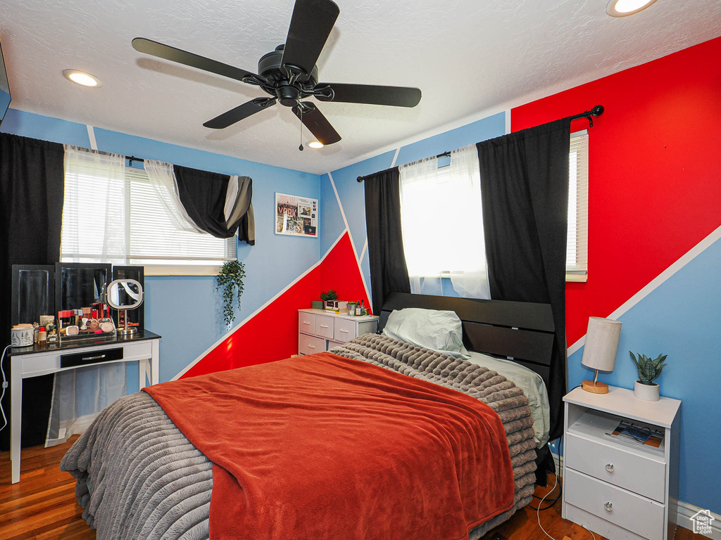 Bedroom featuring a textured ceiling, multiple windows, wood finished floors, and ceiling fan