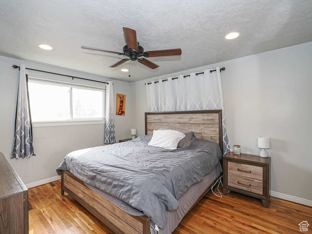 Bedroom featuring recessed lighting, wood finished floors, baseboards, and a textured ceiling