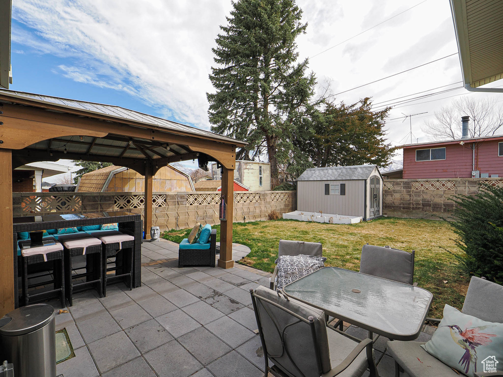 View of patio featuring an outbuilding, outdoor dining space, a fenced backyard, a shed, and an outdoor hangout area