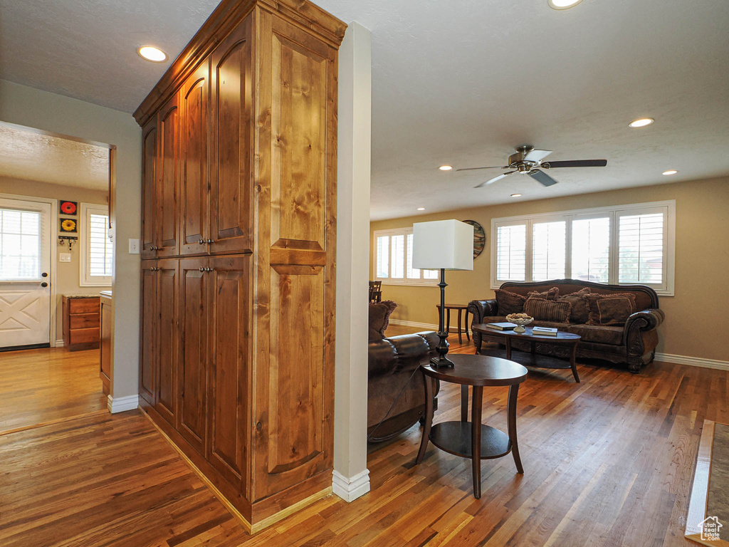 Living room featuring hardwood / wood-style flooring, a ceiling fan, baseboards, and a wealth of natural light