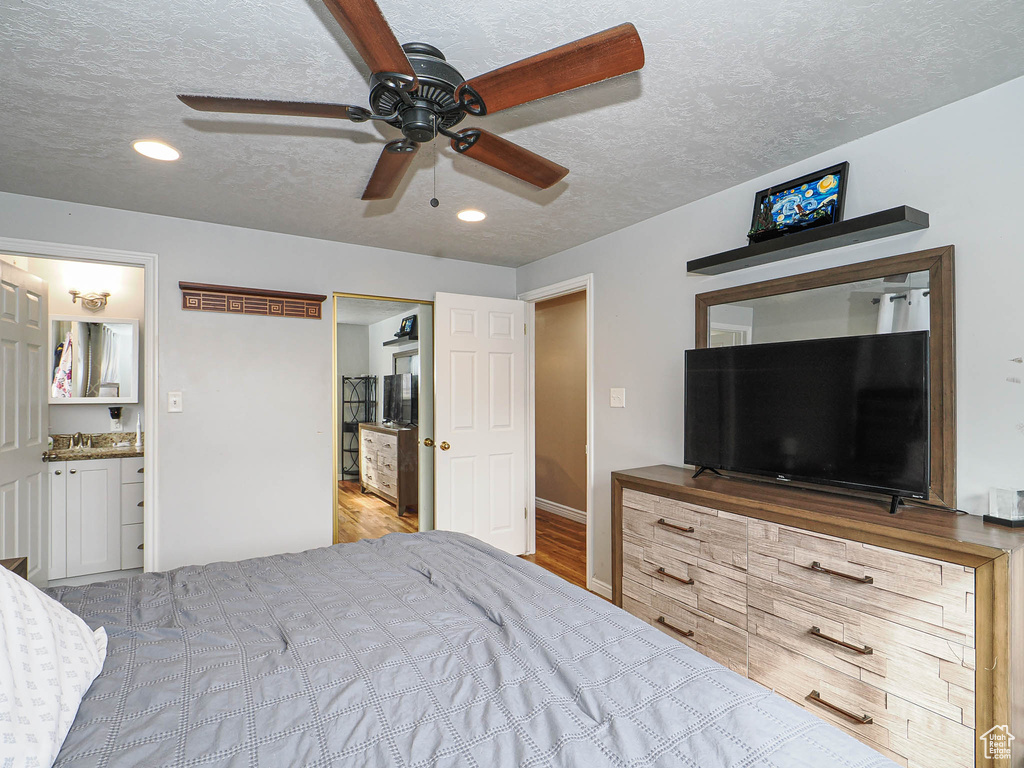 Bedroom with a ceiling fan, ensuite bathroom, a textured ceiling, wood finished floors, and recessed lighting