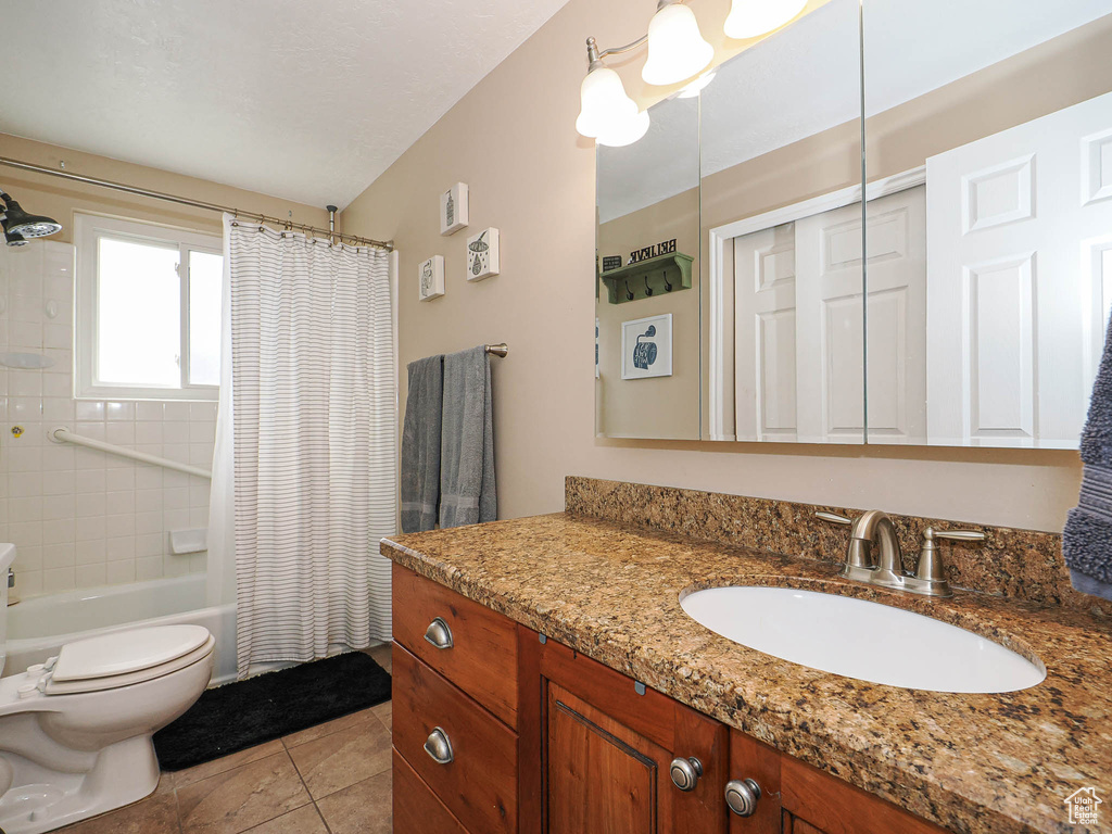 Full bathroom with tile patterned floors, toilet, vanity, and shower / tub combo