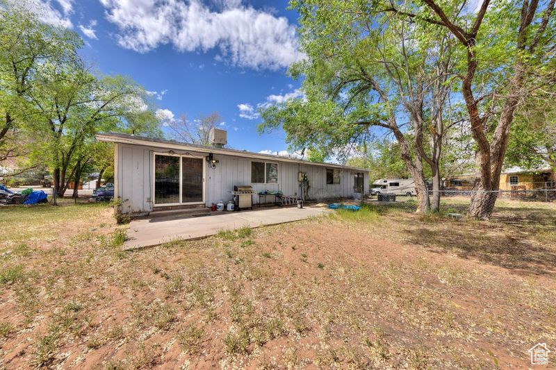 Back of property with fence, a chimney, board and batten siding, and a patio area
