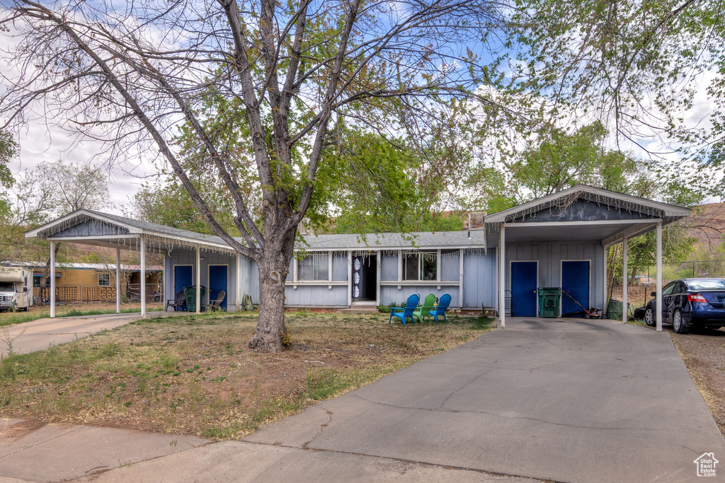 Single story home featuring driveway, board and batten siding, and a detached carport