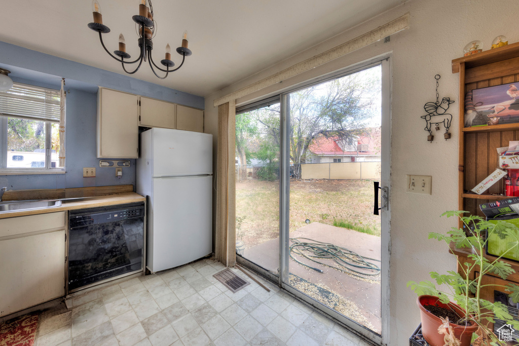 Kitchen with black dishwasher, a wealth of natural light, freestanding refrigerator, and a sink