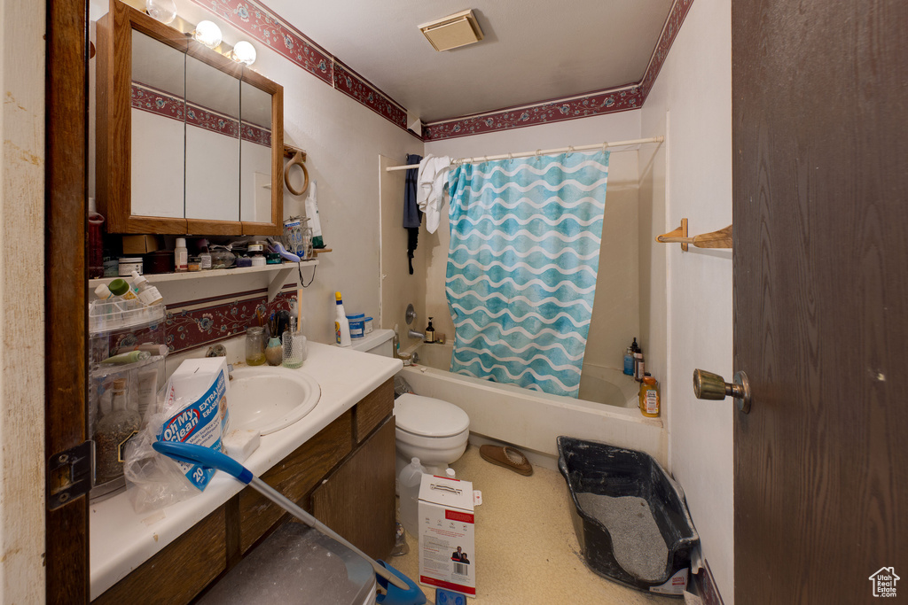 Bathroom with shower / bath combo with shower curtain, vanity, and toilet