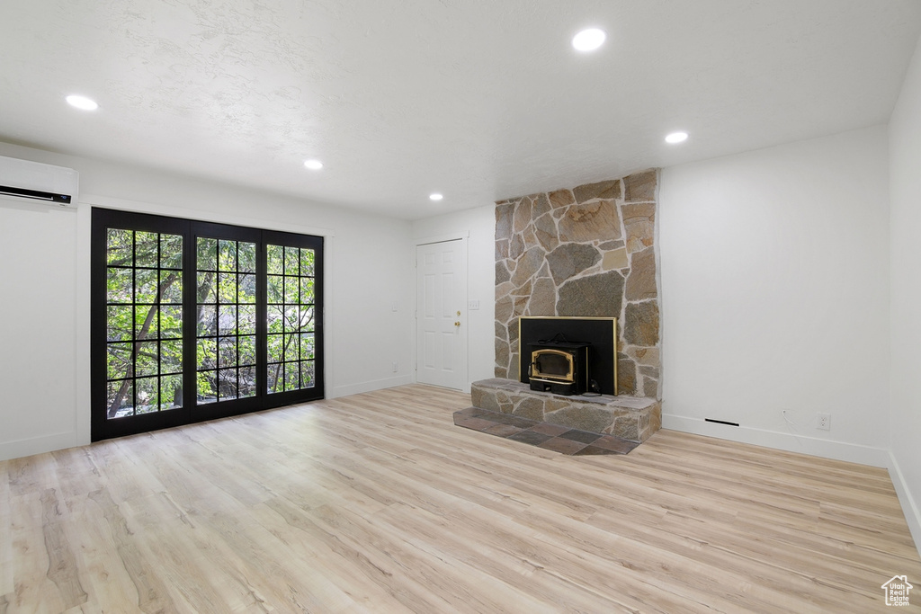 Unfurnished living room with recessed lighting, an AC wall unit, baseboards, and wood finished floors