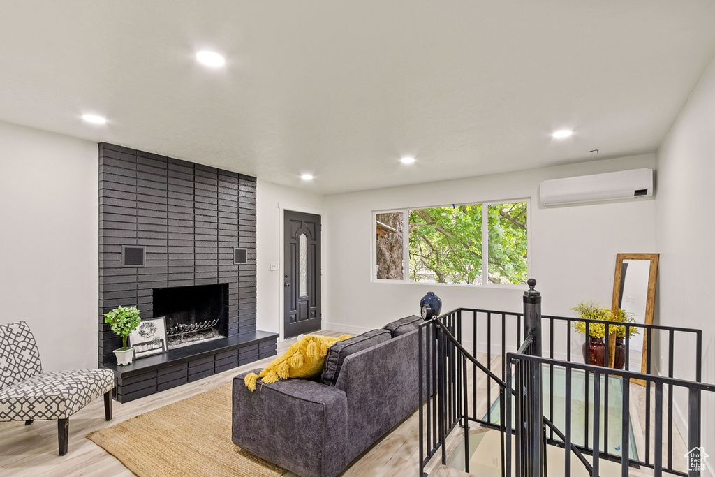 Living area with recessed lighting, a fireplace, a wall mounted AC, and wood finished floors