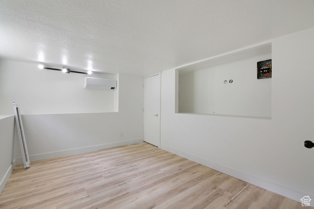 Spare room featuring a textured ceiling, wood finished floors, baseboards, and a wall mounted AC