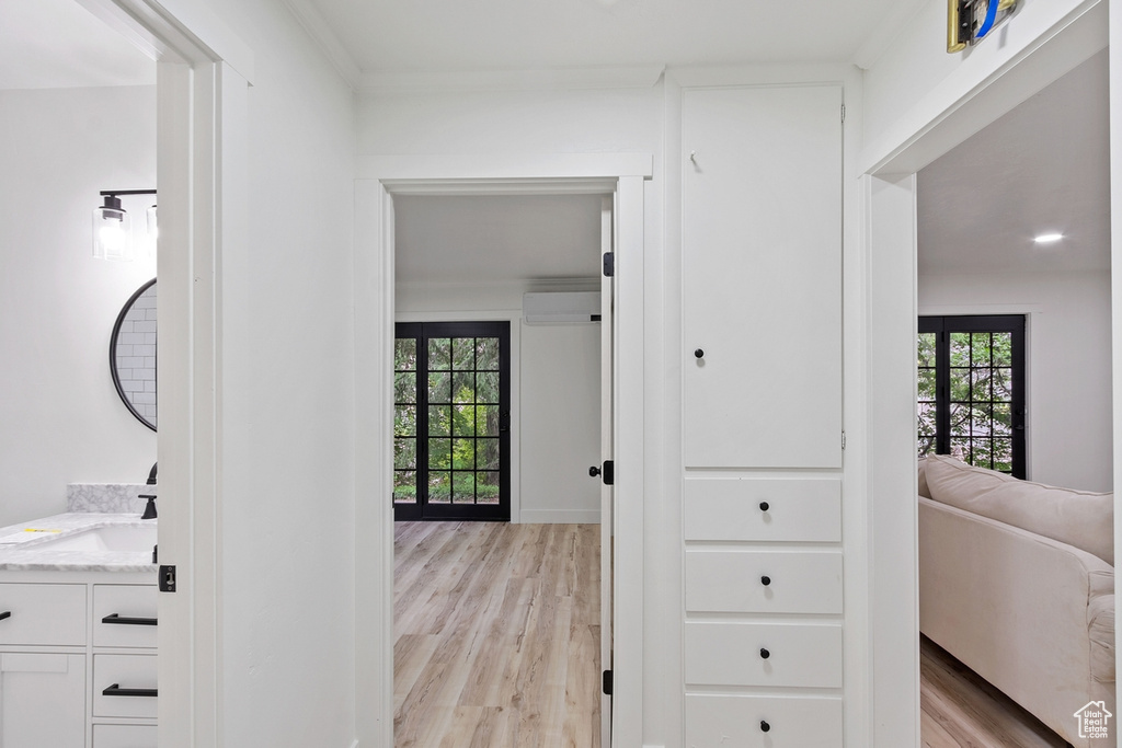 Hall featuring plenty of natural light, a wall mounted air conditioner, light wood-style floors, and a sink