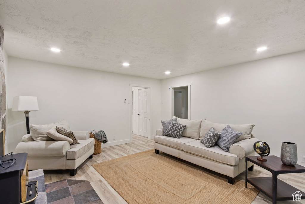 Living area featuring recessed lighting, wood finished floors, baseboards, and a textured ceiling