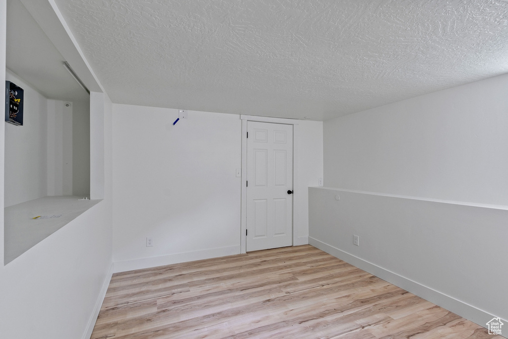 Unfurnished room featuring a textured ceiling, baseboards, and wood finished floors