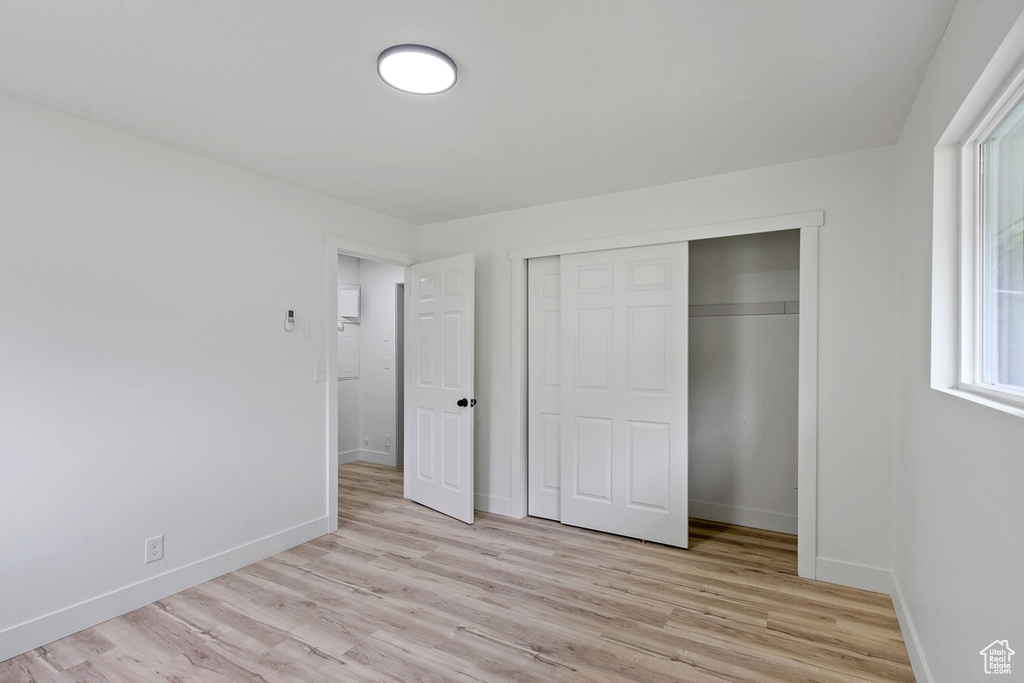 Unfurnished bedroom with light wood finished floors, a closet, and baseboards