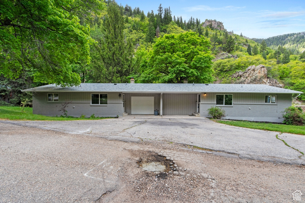 Single story home with brick siding, an attached carport, driveway, and a garage