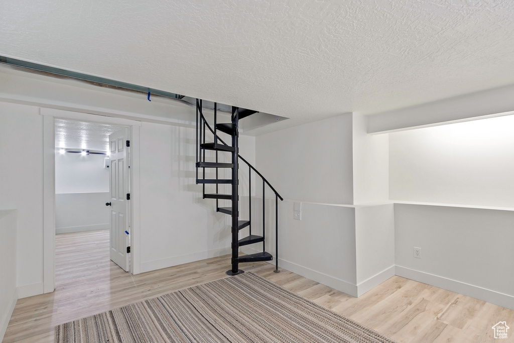 Interior space with a textured ceiling, baseboards, and wood finished floors