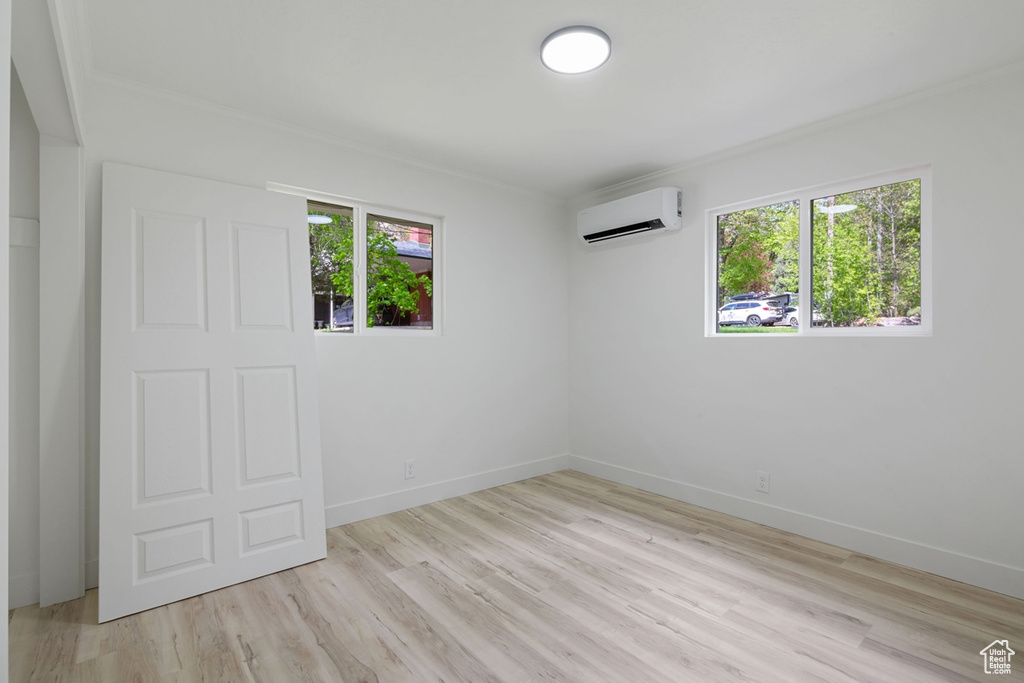 Interior space featuring baseboards, an AC wall unit, and light wood-style floors