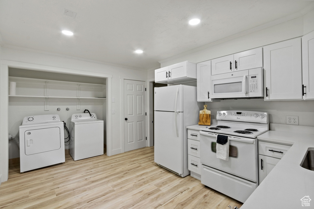 Kitchen with independent washer and dryer, white cabinetry, white appliances, crown molding, and light countertops