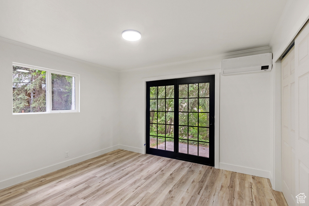 Unfurnished room featuring an AC wall unit, plenty of natural light, and light wood-type flooring
