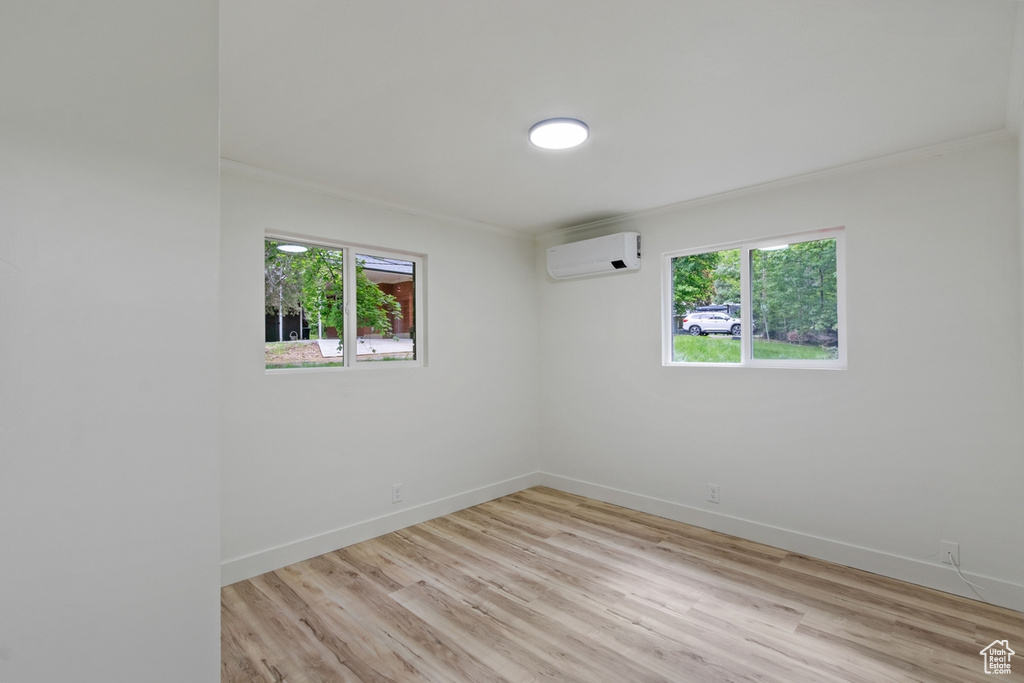 Unfurnished room featuring a wealth of natural light, light wood-style flooring, and a wall mounted air conditioner