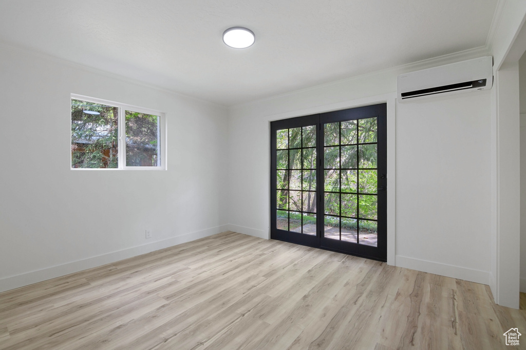 Unfurnished room with a wealth of natural light, baseboards, light wood-style flooring, and a wall unit AC
