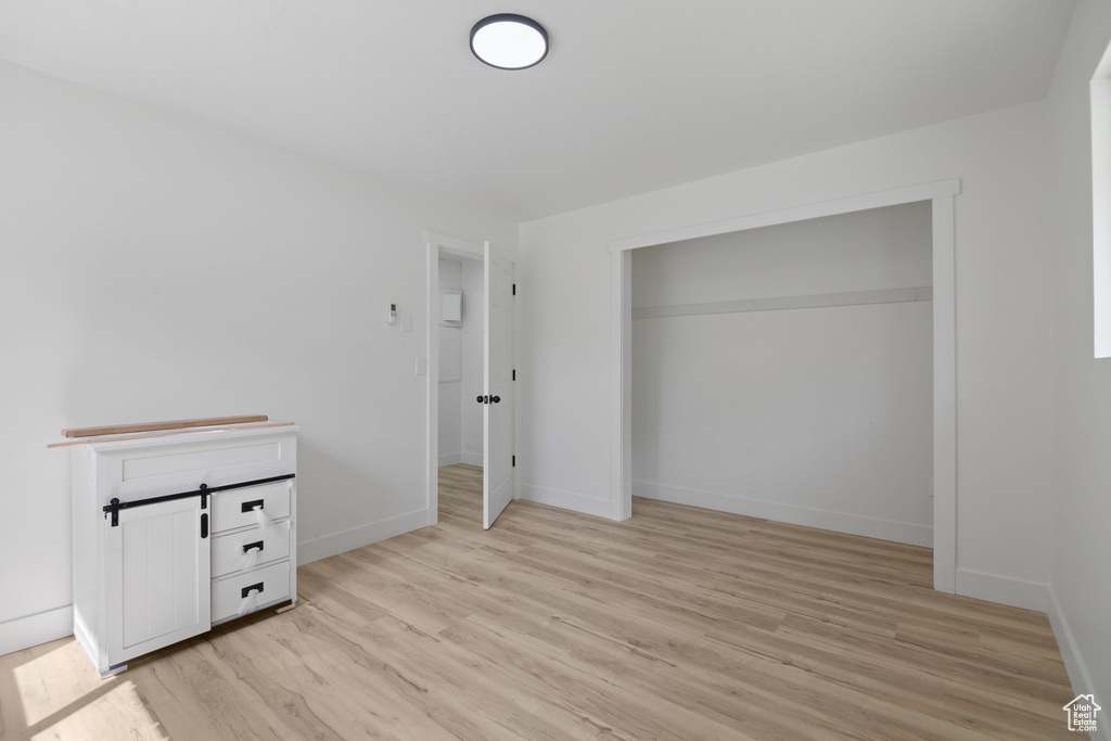 Unfurnished bedroom with light wood-style floors and baseboards