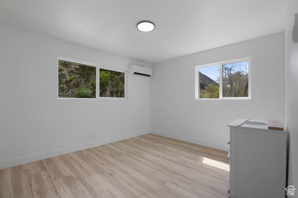 Spare room featuring a wall mounted air conditioner, baseboards, and light wood finished floors
