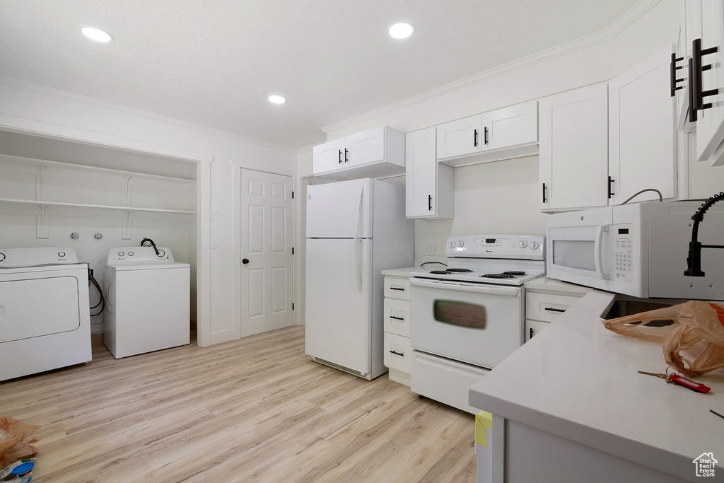 Kitchen with crown molding, light wood-style flooring, white cabinets, white appliances, and separate washer and dryer