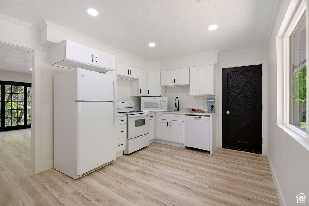 Kitchen with a sink, white appliances, white cabinetry, and ornamental molding