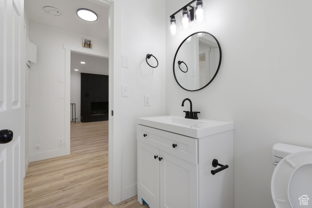 Half bathroom with vanity, toilet, wood finished floors, and baseboards