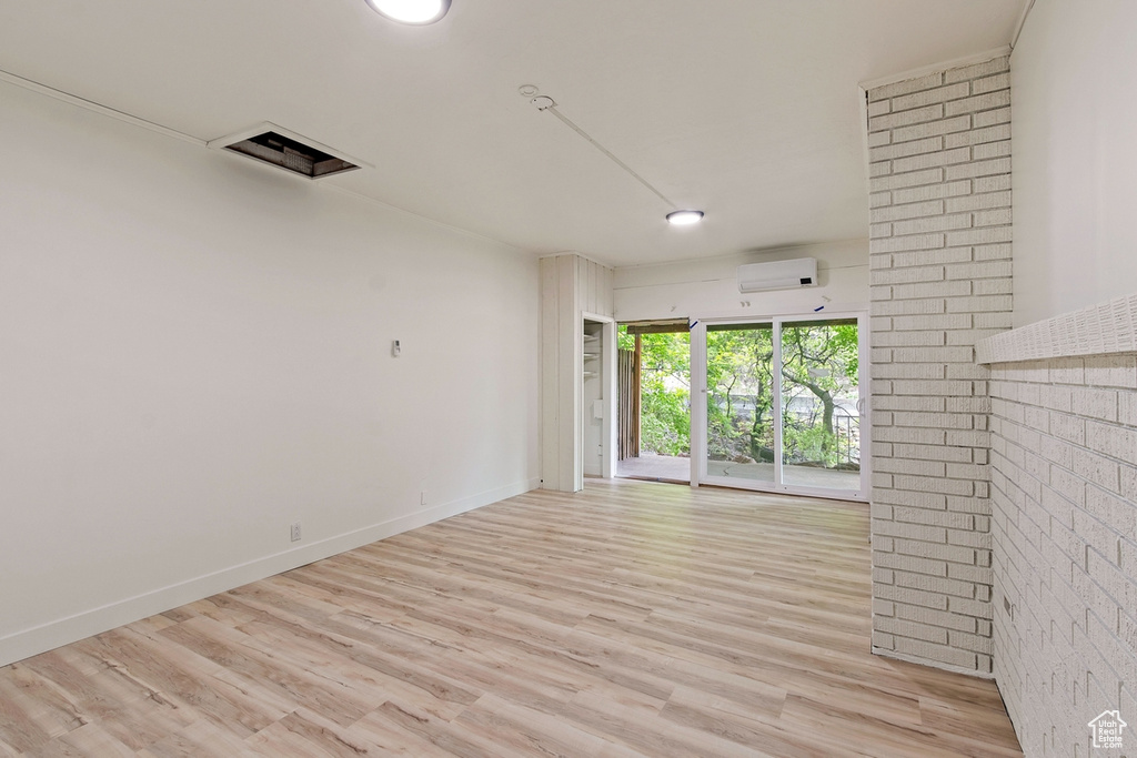 Empty room featuring baseboards, an AC wall unit, and wood finished floors