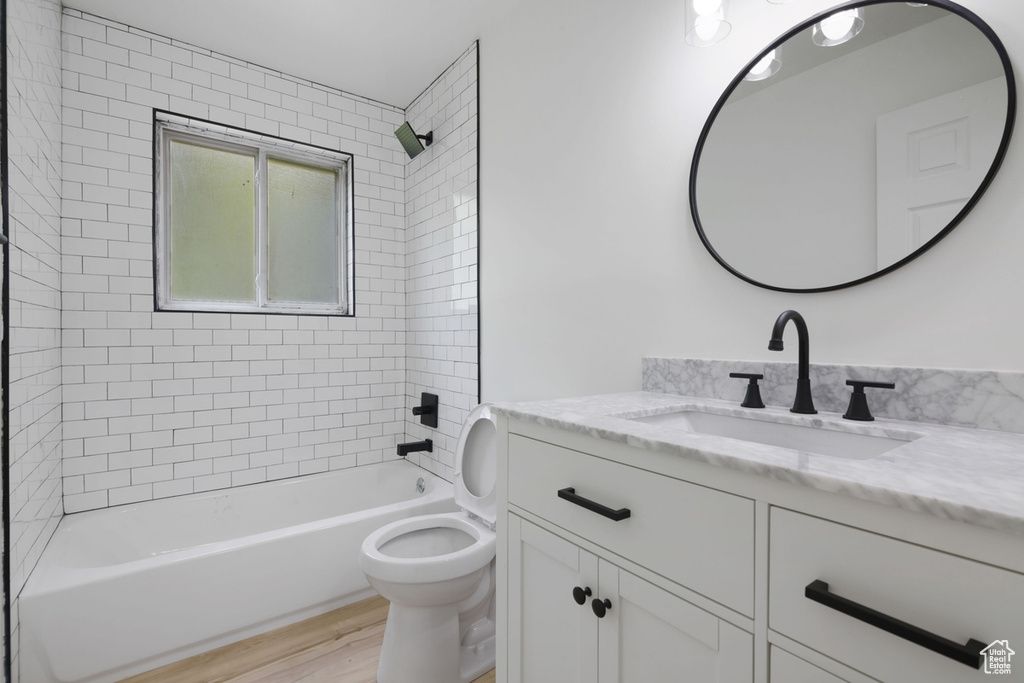 Bathroom with vanity, bathing tub / shower combination, toilet, and wood finished floors