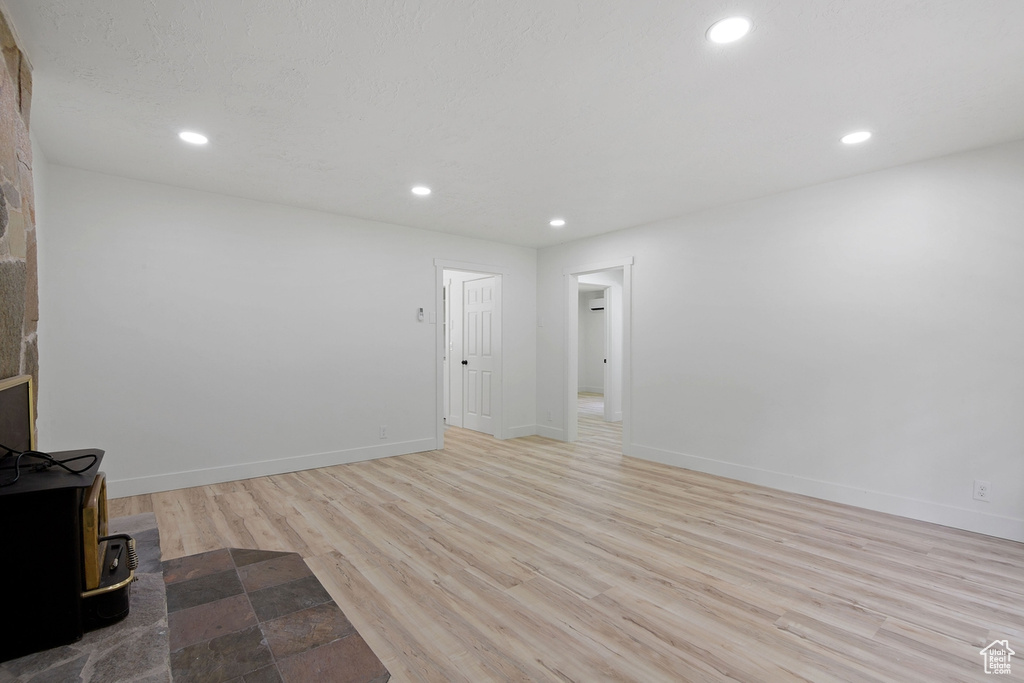 Unfurnished living room featuring recessed lighting, baseboards, light wood-style flooring, and a wood stove