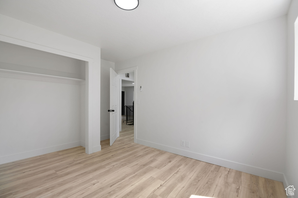 Unfurnished bedroom with a closet, baseboards, and light wood finished floors