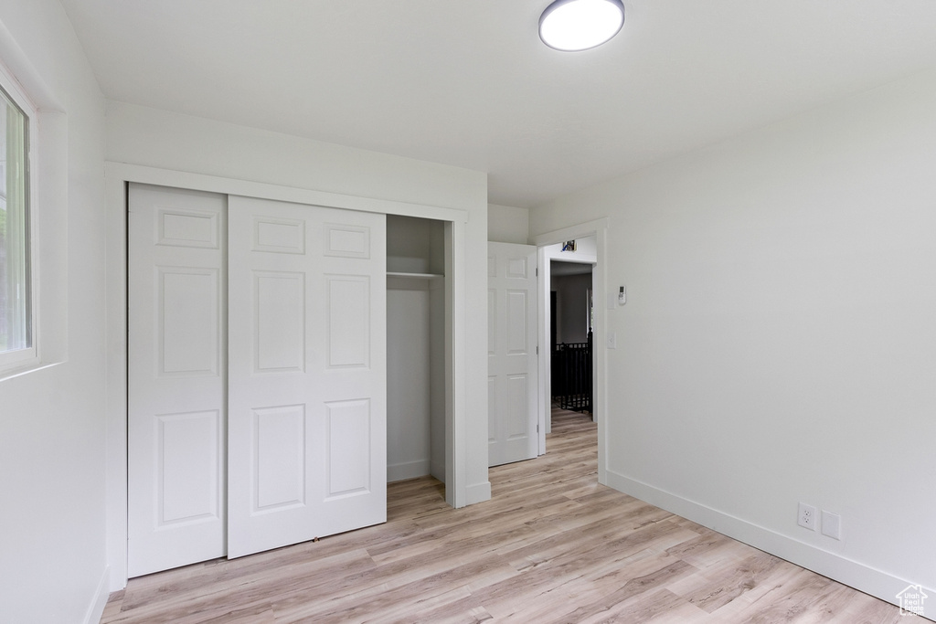 Unfurnished bedroom with baseboards, a closet, and light wood-type flooring