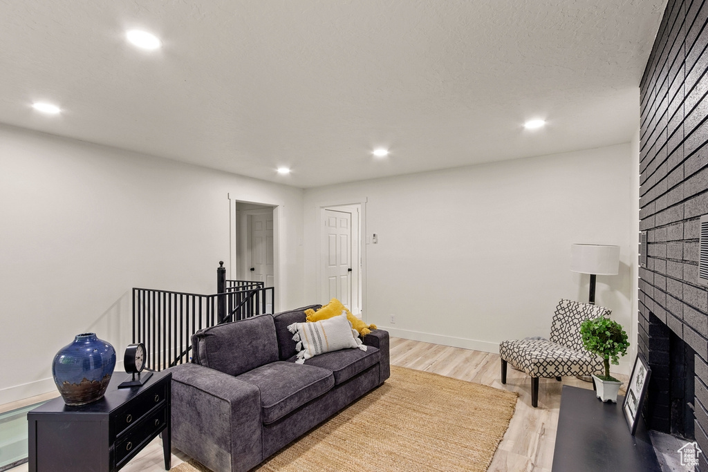 Living area featuring recessed lighting, baseboards, a fireplace, and light wood finished floors