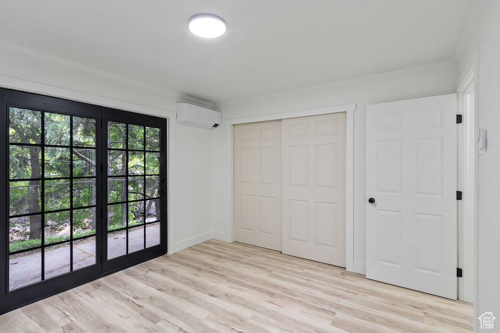 Unfurnished bedroom featuring an AC wall unit, light wood-type flooring, and a closet