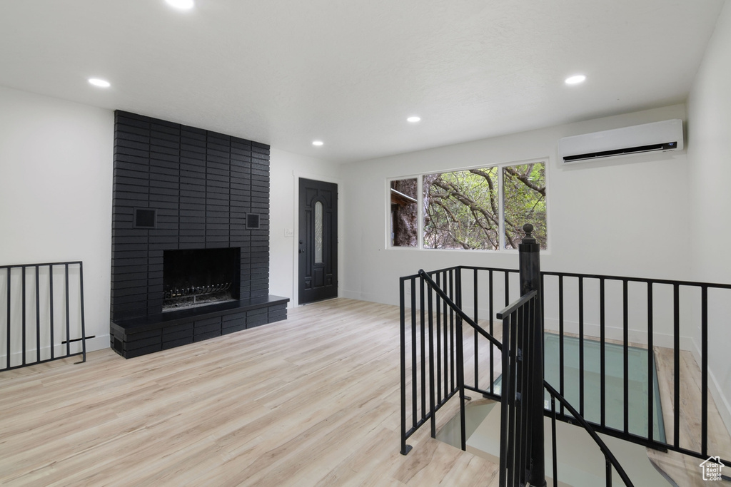Interior space featuring recessed lighting, an AC wall unit, wood finished floors, and a fireplace
