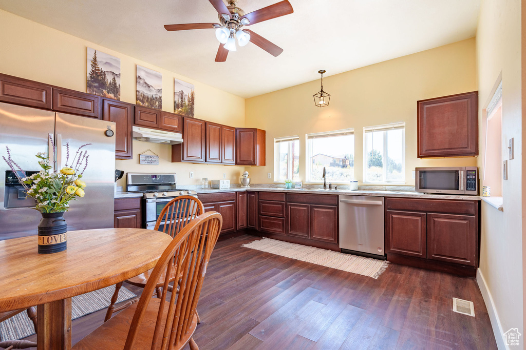 Kitchen featuring visible vents, light countertops, dark wood-type flooring, under cabinet range hood, and appliances with stainless steel finishes