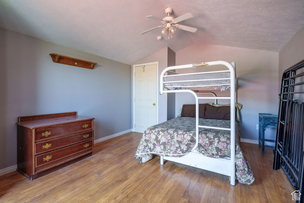 Bedroom with vaulted ceiling, baseboards, and wood finished floors