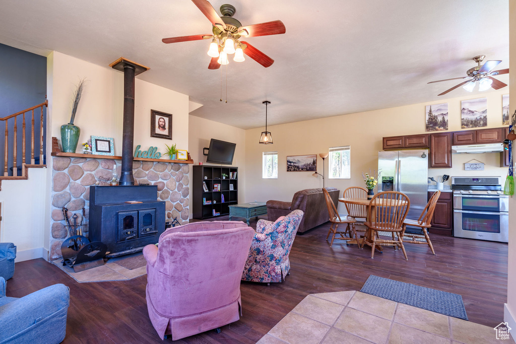 Living area featuring a wood stove, wood finished floors, and ceiling fan