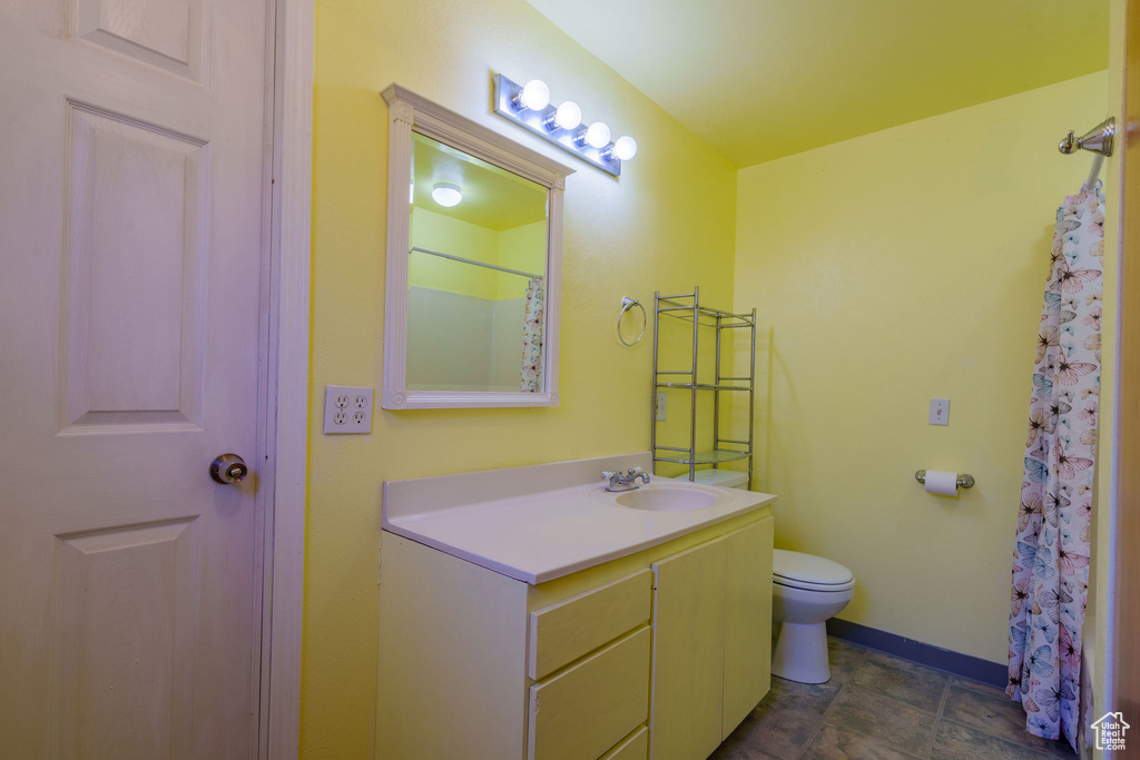 Bathroom featuring vanity, toilet, and baseboards