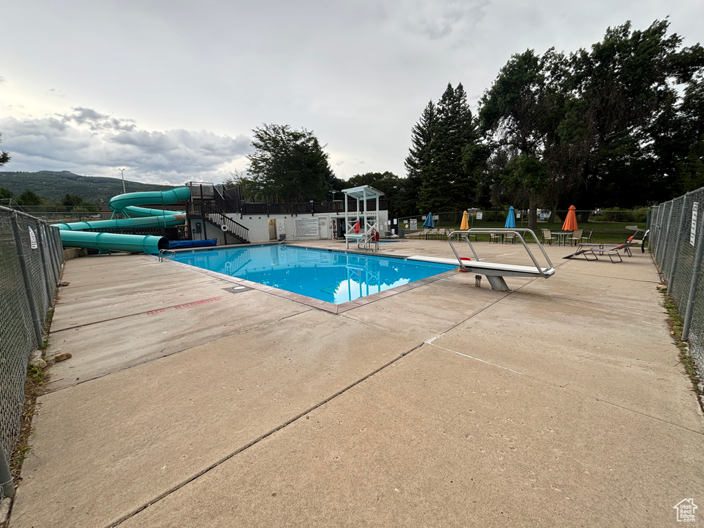 Community pool with a patio, fence, playground community, and a water slide