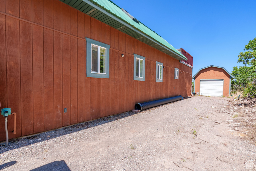 View of side of home with an outdoor structure, a garage, driveway, and metal roof