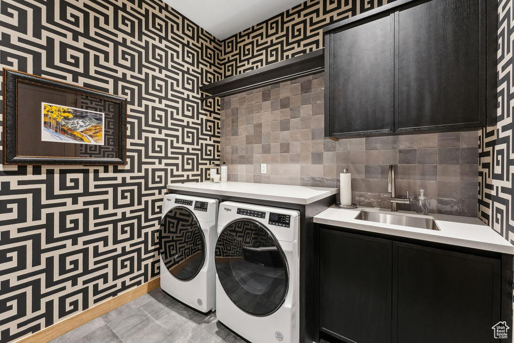 Washroom with a sink, cabinet space, and washer and clothes dryer