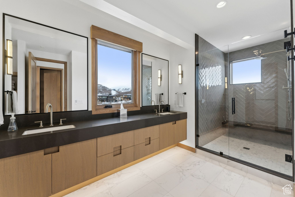 Full bath with double vanity, marble finish floor, a stall shower, and a sink