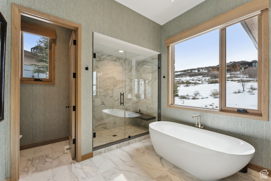Full bathroom with wallpapered walls, plenty of natural light, and marble finish floor