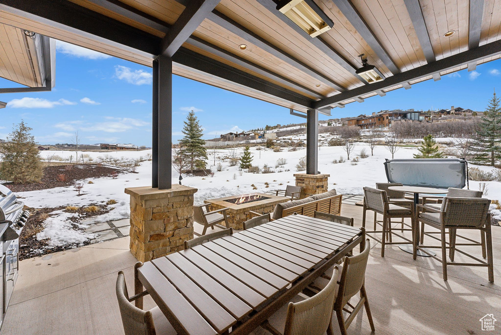 Snow covered patio featuring outdoor dining area and an outdoor fire pit