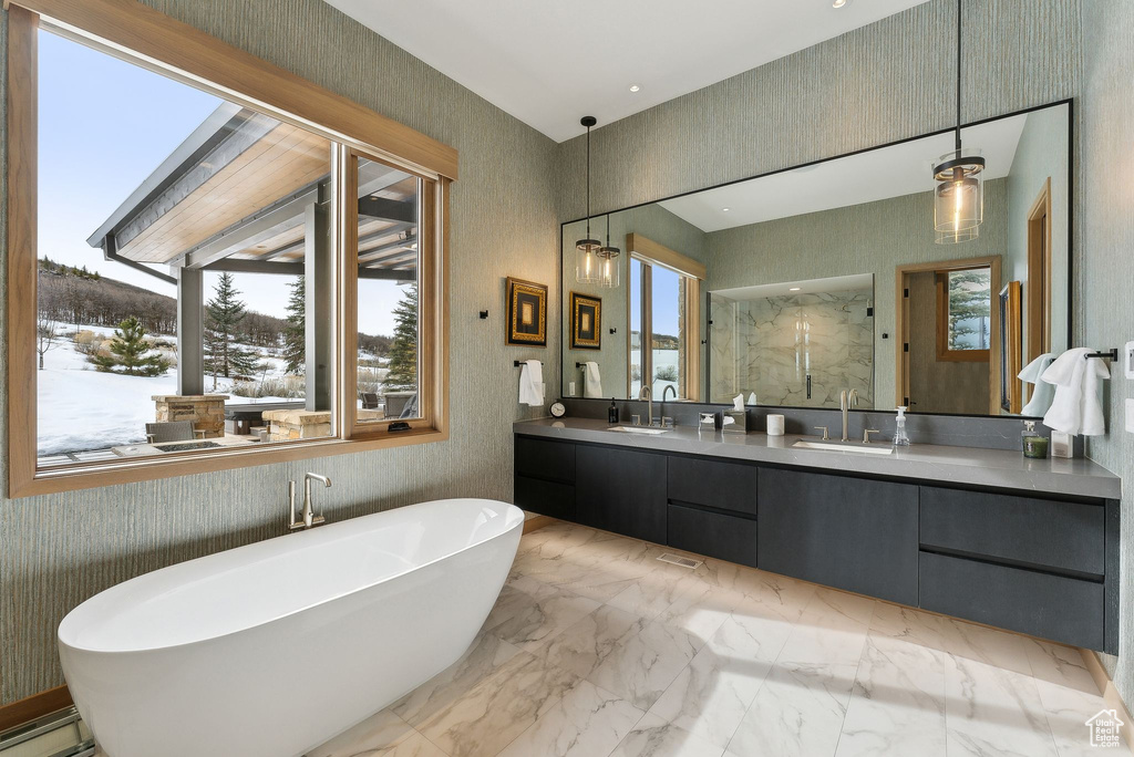 Bathroom featuring a soaking tub, marble finish floor, a marble finish shower, and a sink